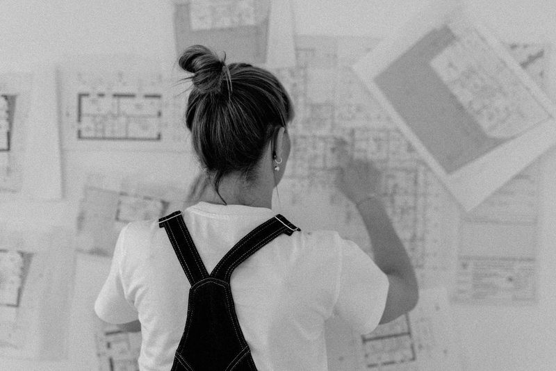 Katharina Keimelmayr von hinten vor einer Wand mit Grundrissplänen